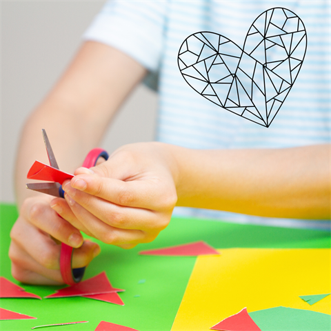 A child sits cutting out shapes from coloured paper