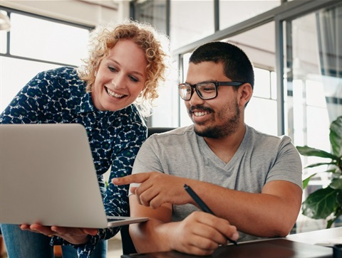 Two people looking up information on a laptop together